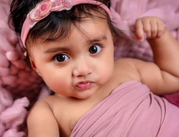 a baby girl in a pink dress and headband