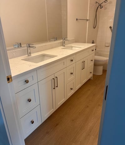 Modern bathroom with double-sink white shaker vanity, quartz countertop, and wood-look flooring — RT