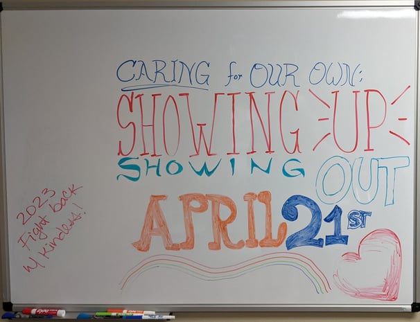 photo: whiteboard reads "CARING FOR OUR OWN: SHOWING UP, SHOWING OUT, APRIL 21ST; 2023 Fight back w/kindness"