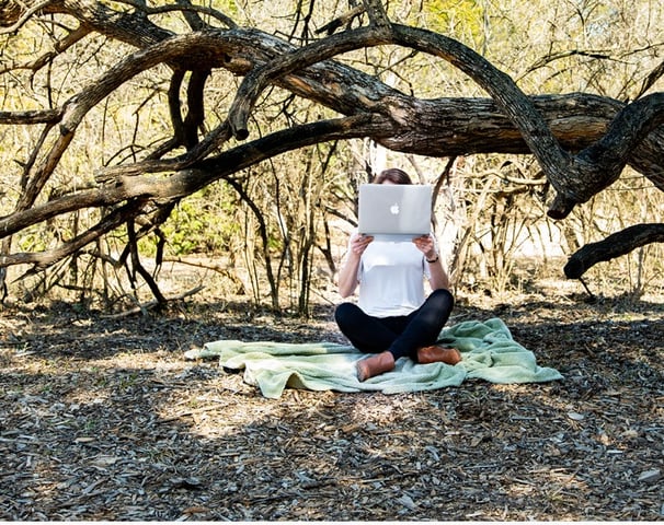 girl with laptop in woods hiding face