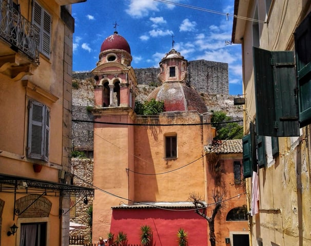 a motorcycle parked in a narrow alley with a red wall