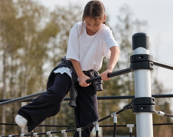 Fille grimpant sur une structure Kenguru Pro Kids Active Play en extérieur.