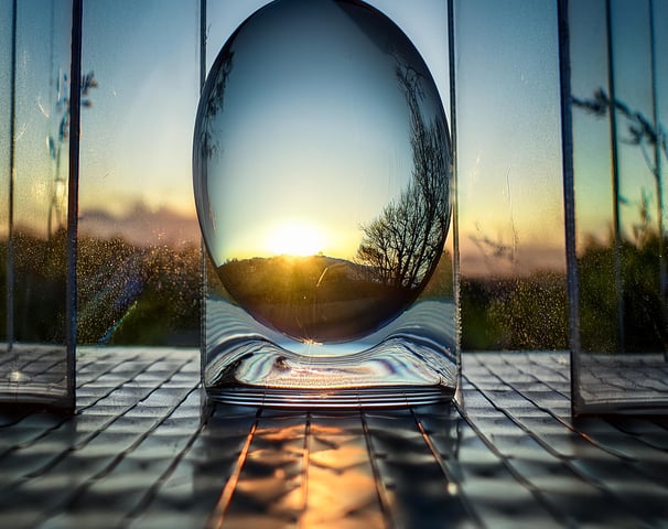 An AI generated image of a transparent glassy egg in front of a window at sunset