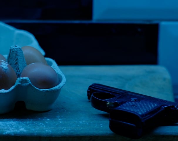 A still frame from the short film that consists of a box of eggs and a gun covered in flour