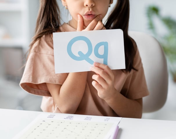 Een jong meisje dat een papieren bord vasthoudt met de tekst "qq"