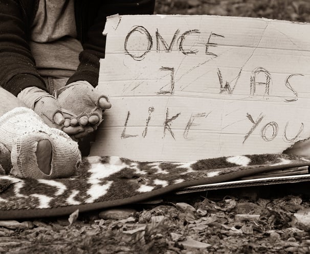 a person sitting on a blanket with a sign that says one of the signs