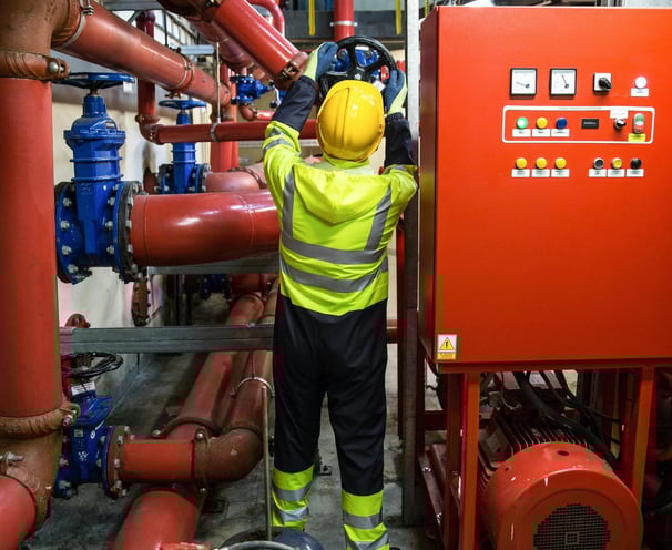 Maintenance worker turning a valvue for a industrial machine