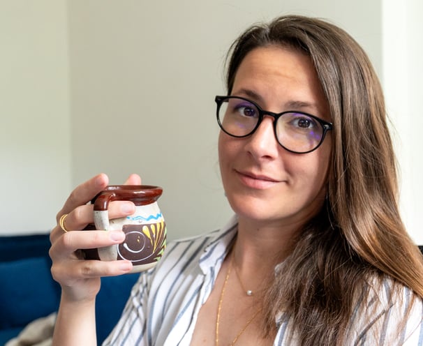 a woman in glasses and a striped shirt is holding a cup of coffee