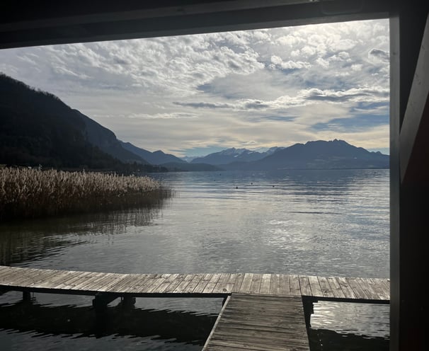 Vue depuis un ponton sur le lac d'Annecy avec au loin les montagnes