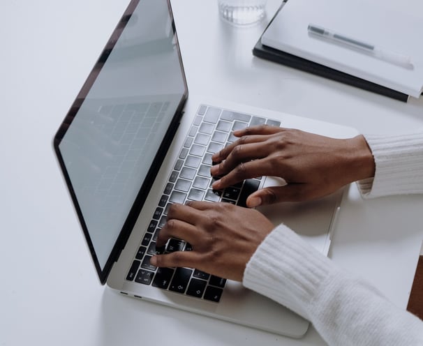 a person sitting at a table with a laptop and a glass of water