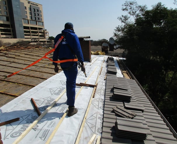 Environmental Pro Construction installing SABS-compliant roof sheeting under safety harness in West