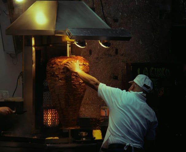 a man is cooking/heating meat for Street Local tacos at Tacos Mixes Los Angeles