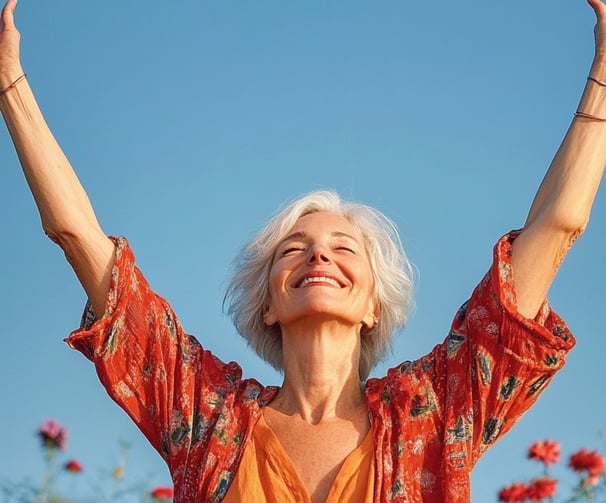 Mujer mayor levantando las manos hacia el sol y sonriendo 