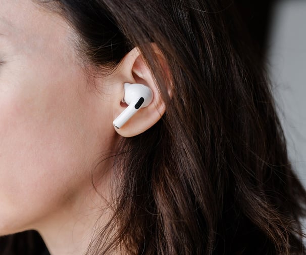Profile of a women with long, dark hair, with air pods in her ears.