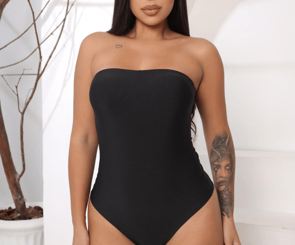 a woman in a black swimsuit with tattoos on her chest