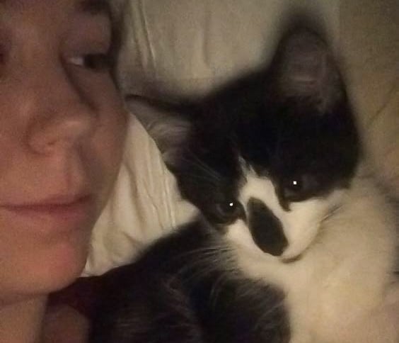 woman laying with black and white kitten