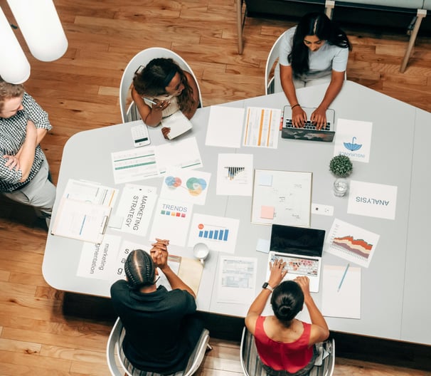 Equipo de marketing reunido alrededor de una mesa analizando gráficos y datos estratégicos para camp