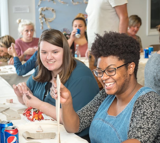 Individuals at a private party laughing as they begin their clay project.