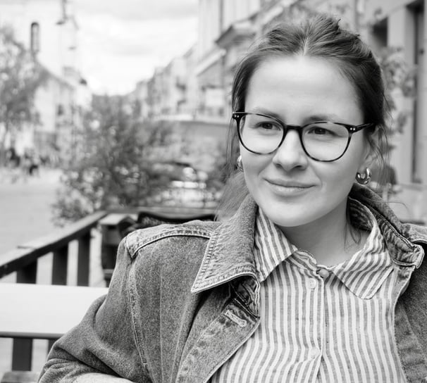 a woman in glasses and a jacket is sitting on a bench