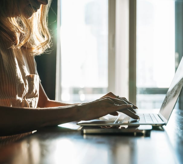 A woman with long blonde hair working on a laptop.