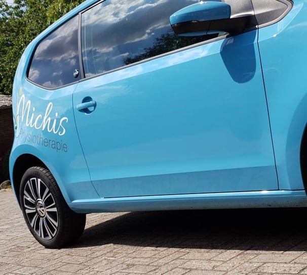 a blue car parked signed michis physio on a brick road