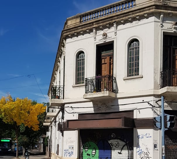 Front of the Spanish school in Rosario with graffiti and a tree with yellow leaves