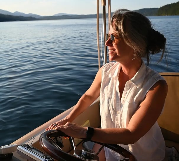a beautiful woman in a white shirt is sitting on a eco-friendly electric boat cruising hood canal