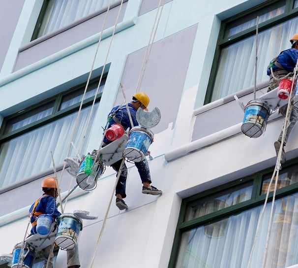 um grupo de pintores pintando uma fachada de um condominio