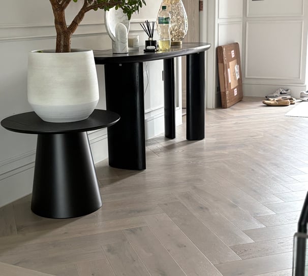 A light oak herringbone floor in a hallway with a step and small tables
