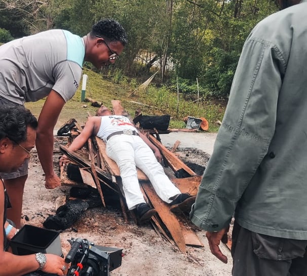 a film crew hard at work shooting a man in a white shirt