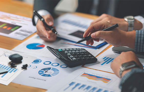 a person sitting at a desk with a calculator and a pen