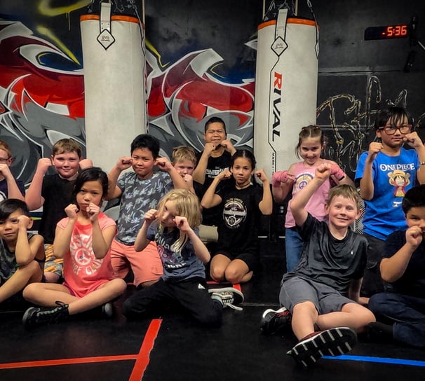 a group of children and the coach posing with their fists raised