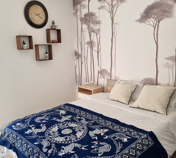 a bed with a blue blanket and a clock on the wall