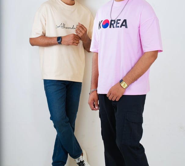 two men standing next to each other in front of a white wall