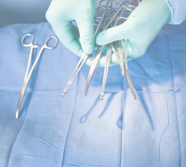a doctor in a blue gloved hand holding surgical tools