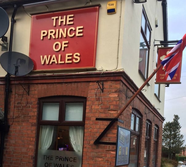 a flag flying in front of a pub with a sign saying THE PRINCE OF WALES