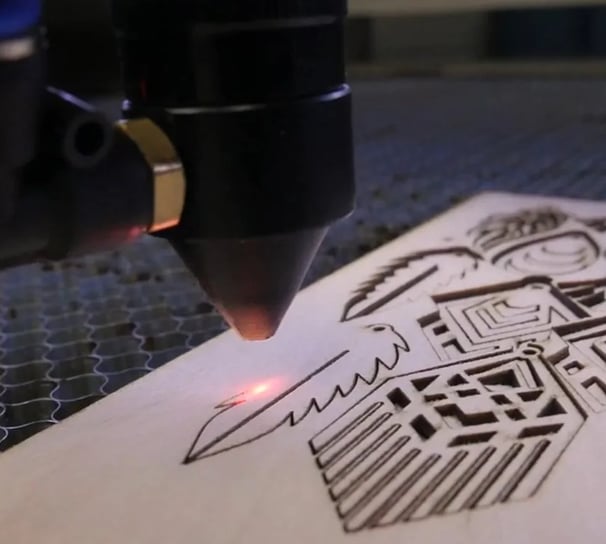 Una máquina de grabado láser en el proceso de cortar de una placa de madera