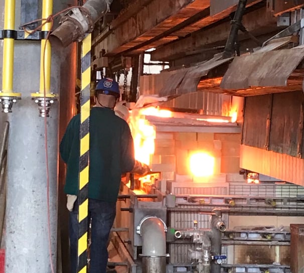 a man in a green shirt is standing in a factory