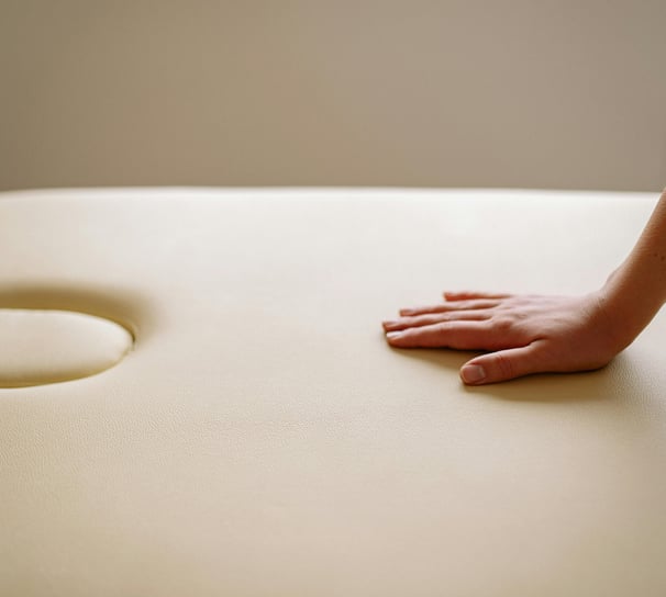 Main posée sur ma table de massage couleur crème, ambiance relaxante