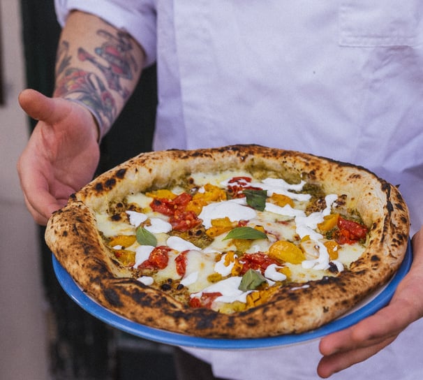 a man in a chef's uniform holding a pizza