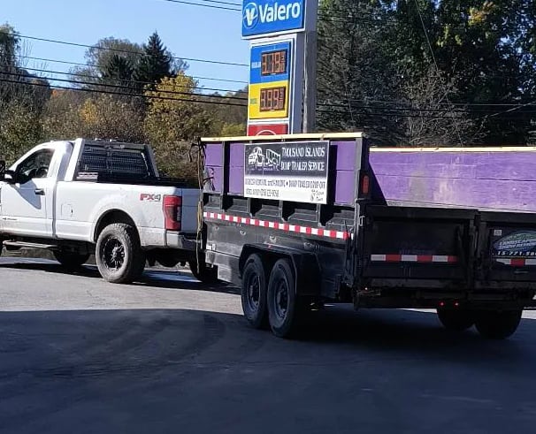 A Truck pulling a purple dump trailer branded for TI Dump Trailers