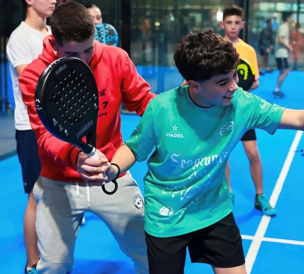 Padel coach demonstrating shot technique during group training session near Barcelona
