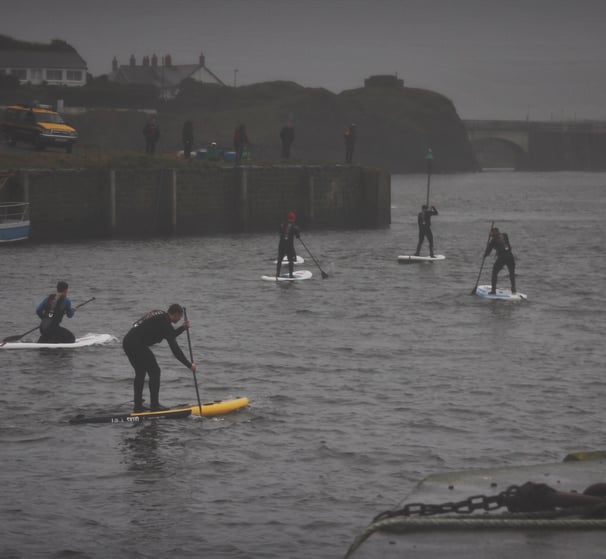 A paddle board race in Aberystwyth harbour on a grey December day