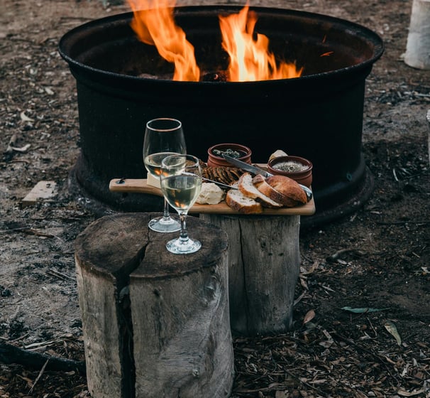 a glass of wine and bread on a table near open fire