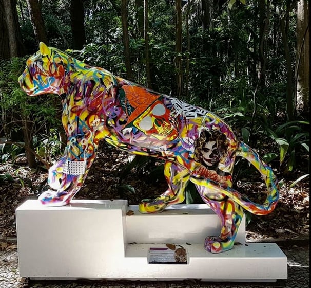 Uma escultura vibrante de onça-pintada com padrões coloridos, situada no Parque do Masp