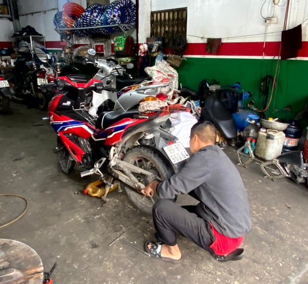 a man in a gray shirt is working on a motorcycle