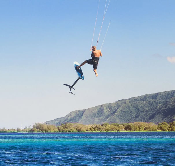 Kaituodamas su kite foil sportininkas išoką į orą virš vandens.