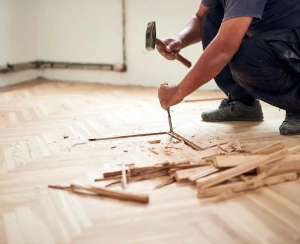 ouvrier qui casse du parquet au sol