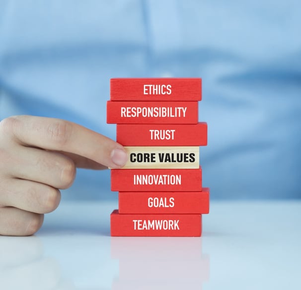 a person holding a stack of red blocks and one white block with the word core values