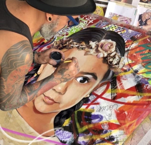 Sérgio Astral em seu estúdio, trabalhando em uma pintura à mão com tinta acrílica e spray.